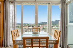 - une salle à manger avec une table, des chaises et de grandes fenêtres dans l'établissement Hauzify I Apartament Parera, à Platja d'Aro