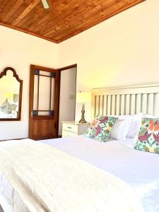 a bedroom with a white bed with a wooden ceiling at Eikelaan Farm Cottages in Tulbagh
