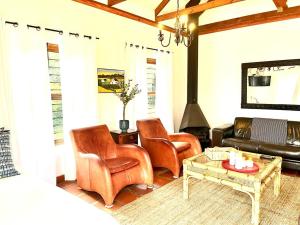 een woonkamer met lederen stoelen en een open haard bij Eikelaan Farm Cottages in Tulbagh