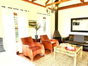 a living room with leather chairs and a fireplace at Eikelaan Farm Cottages in Tulbagh