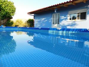 a blue swimming pool next to a blue house at M & M House in Ayiá