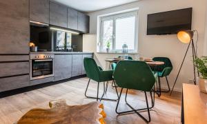 cocina y comedor con mesa y sillas verdes en Arbio I Cozy Apartment Augsburg-Göggingen, en Augsburg