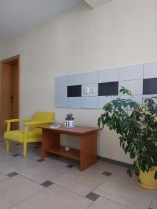 a waiting room with a yellow chair and a desk at PS Apartments - Peshtani in Peštani
