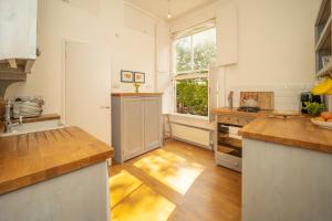 een keuken met witte muren en houten vloeren en een raam bij Studio Apartment in Central Bath in Bath