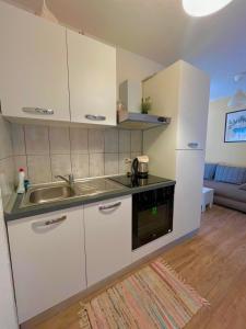 uma cozinha com armários brancos e um lavatório em Villa Anita em Sobra