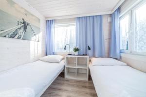 two beds in a small room with blue curtains at ASTORIA-Ruszel domki letniskowe in Dziwnów