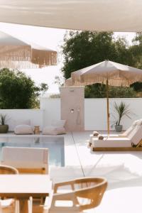 a pool with white furniture and an umbrella at Merelia Exclusive Villas in Parga