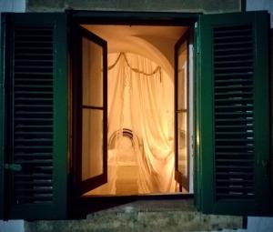 uma janela aberta de um quarto com uma cortina em Villa Tessi em Cisternino