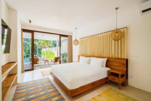 a bedroom with a large bed and a balcony at Beefy Dragon Villa by Betterplace in Dalung
