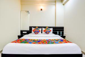 une chambre avec un grand lit blanc avec des oreillers colorés dans l'établissement FabHotel Sai Govind, à Shirdi