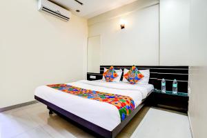 une chambre avec un grand lit avec des oreillers colorés dans l'établissement FabHotel Sai Govind, à Shirdi