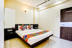 une chambre avec un grand lit avec des oreillers colorés dans l'établissement FabHotel Sai Govind, à Shirdi