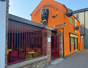 ein orangefarbenes Gebäude mit einem Geschäft mit Tischen und Stühlen in der Unterkunft Bugler Doyles Bar & Townhouse in Wexford