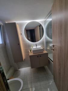 W łazience znajduje się umywalka i lustro. w obiekcie Piraeus open view Appartment w Pireusie