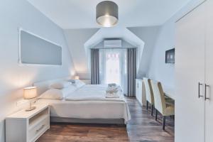 a white bedroom with a bed and a window at Tokajer Wellness Panzió in Keszthely