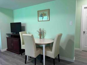 - une salle à manger avec une table, des chaises et une télévision dans l'établissement Countryroad Cozy 2 Bedrooms basement suite1, à Nanaimo