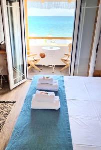 two towels sitting on the floor in a room with the ocean at Votsalo Cozy Apartments in Limenaria