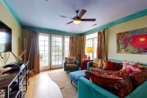 uma sala de estar com um sofá azul e uma ventoinha de tecto em Pavilion Watch #2E em Folly Beach