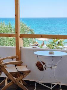 una mesa y una silla en un balcón con vistas a la playa en Votsalo Cozy Apartments en Limenaria