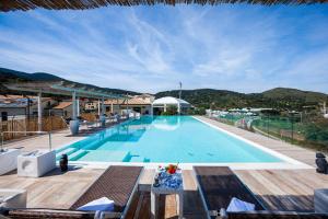 ポルト・エルコレにあるA Point Porto Ercole Resort & Spaの大きなスイミングプール(テーブル、椅子付)