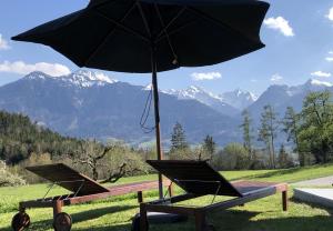 zwei Stühle und ein Regenschirm auf einem Tisch mit Bergen in der Unterkunft Ferienhaus Röns in Röns