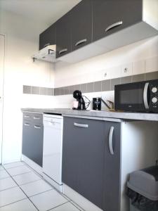 uma cozinha com armários a preto e branco e um micro-ondas em Appartement aux portes de Bordeaux em Pont-de-la-Maye
