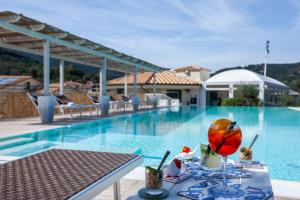 a table with a drink on it next to a swimming pool at A Point Porto Ercole Resort & Spa in Porto Ercole