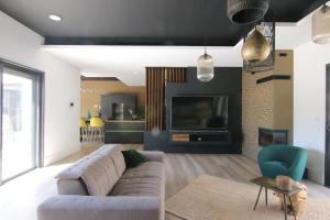 ein Wohnzimmer mit einem Sofa und einem TV in der Unterkunft Villa  Tropicale entre Nîmes Avignon et Arles in Beaucaire