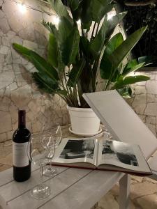 a bottle of wine and a book on a table with glasses at CORTILET in Fasano