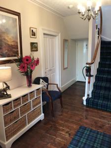 a living room with a staircase and a vase of flowers at The Struan Inn Self Catering Lodge in Struan