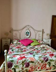 un letto con copriletto floreale e cuscino rosa di A Casa di Marzia a Rapolano Terme