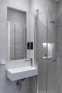 a white bathroom with a sink and a shower at Mornington Victor Hotel London Belgravia in London +16 photos
