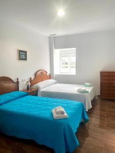 1 dormitorio con 2 camas con sábanas azules y ventana en Casa Campoamor By Solymar Holiday en Cogollos de Guadix