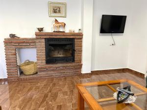 sala de estar con chimenea de ladrillo y TV en Casa Campoamor By Solymar Holiday en Cogollos de Guadix