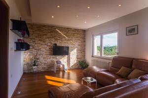 a living room with a leather couch and a brick wall at Apartment Galjanić in Buzdohanj