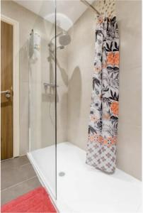 a glass shower in a bathroom with a red rug at Wonderful Family Friendly Cosy Home Free Parking in Crayford