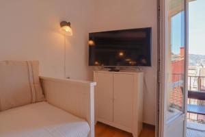 een slaapkamer met een tv aan de muur en een bank bij "La Belle Vue Mer" Cozy Appartement, Centre, Plage in Menton