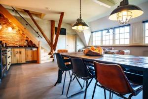 een grote keuken met een grote houten tafel en stoelen bij Loft in romantische stolpboerderij bij duingebied. in Warmenhuizen