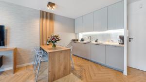 a kitchen with white cabinets and a table with flowers at Apartament Piaskowy C 07- Posesja Kapitańska-Holiday City in Grzybowo