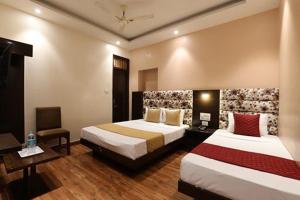 a hotel room with two beds and a desk at Amrit Hotel in New Delhi