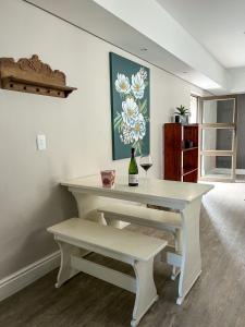 una mesa blanca con una botella de vino y un banco en 6 on Western Guest House, en East London