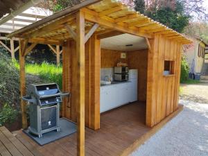 a wooden pergola with a grill on a deck at La Maison de Tari in Vitrac