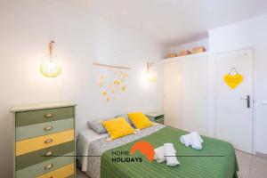 a bedroom with a bed with yellow and green sheets at #006 Foxy D by Home Holidays in Caliços +42 photos