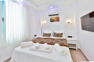 a white bedroom with two beds with towels on them at Carpediem Apart in Kaş