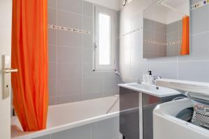 cortina de ducha naranja en el baño con bañera y lavamanos en Sejour apaisant avec vue mer, en Saint Gilles Croix de vie