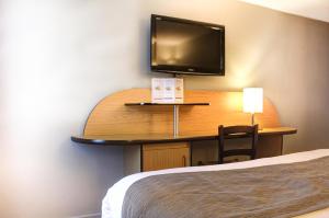 a hotel room with a desk with a tv and a bed at Hôtel Inn Design Resto Novo Bourges in Bourges