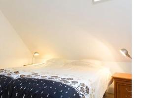 1 cama con edredón blanco y negro y 2 lámparas en Appartement Avondzon in romantische stolpboerderij, en Warmenhuizen