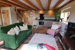a living room with a green couch and a kitchen at Piglet's Hideaway in Stratford-upon-Avon