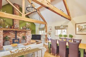 a living room with a brick fireplace and a dining room at Hollington Barns in Ashbourne