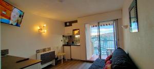 a living room with a couch and a kitchen with a balcony at Studio Cap d'Agde la grande voile in Cap d'Agde